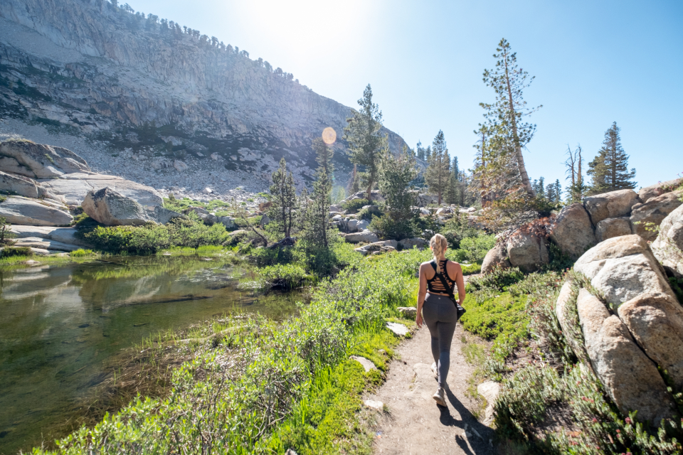 A woman hiking an alpine trail below granite peaks