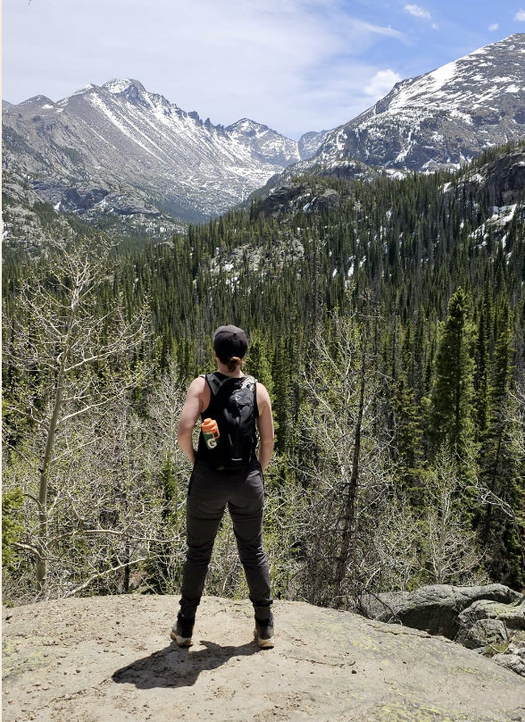 Debra on the trail in Rocky Mountain National Park, looking out to snow-capped peaks